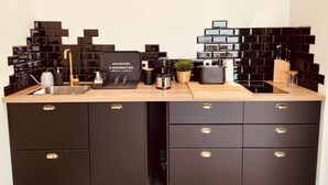 A kitchen with black tiled backsplash, a sink, a toaster, and a coffee maker.