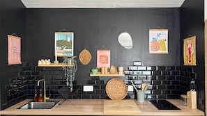 A modern kitchen with black tiled backsplash, wooden countertops, and various kitchen utensils.