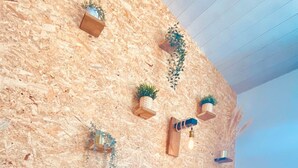 A bedroom with a wooden wall, a bed with blue bedding, and multiple hanging planters.