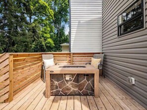 Relax in the patio's warm ambiance, surrounded by a wooden fence and a fireplace.