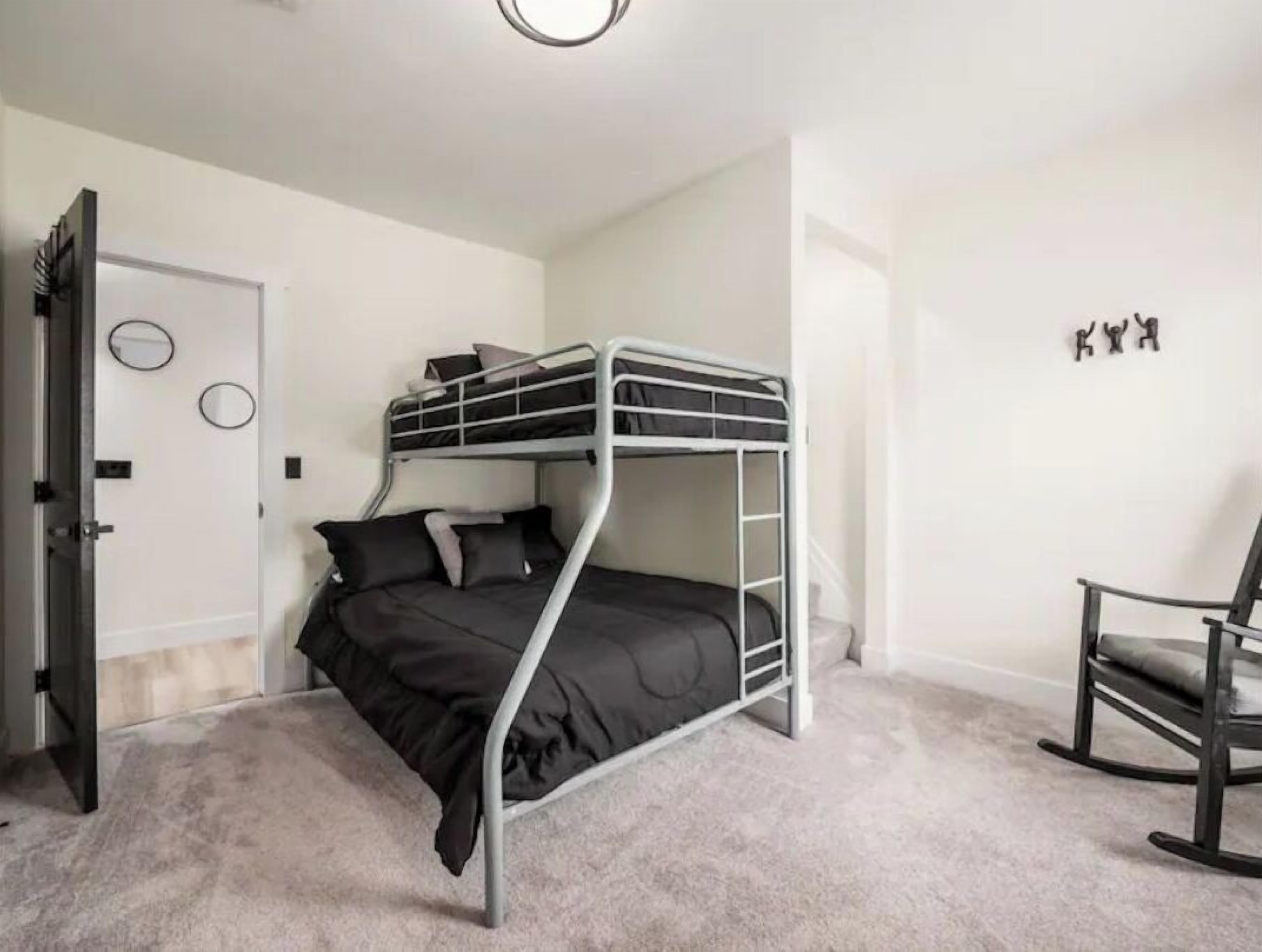 Habitación con literas, una puerta, una silla y un muro decorado con tres círculos.