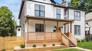 A two-story house with a front porch, a chimney, and a visible address number.