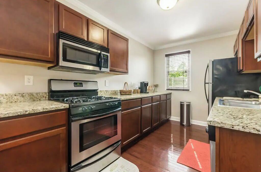A kitchen with wooden cabinets, a stainless steel stove, a microwave, and a refrigerator.