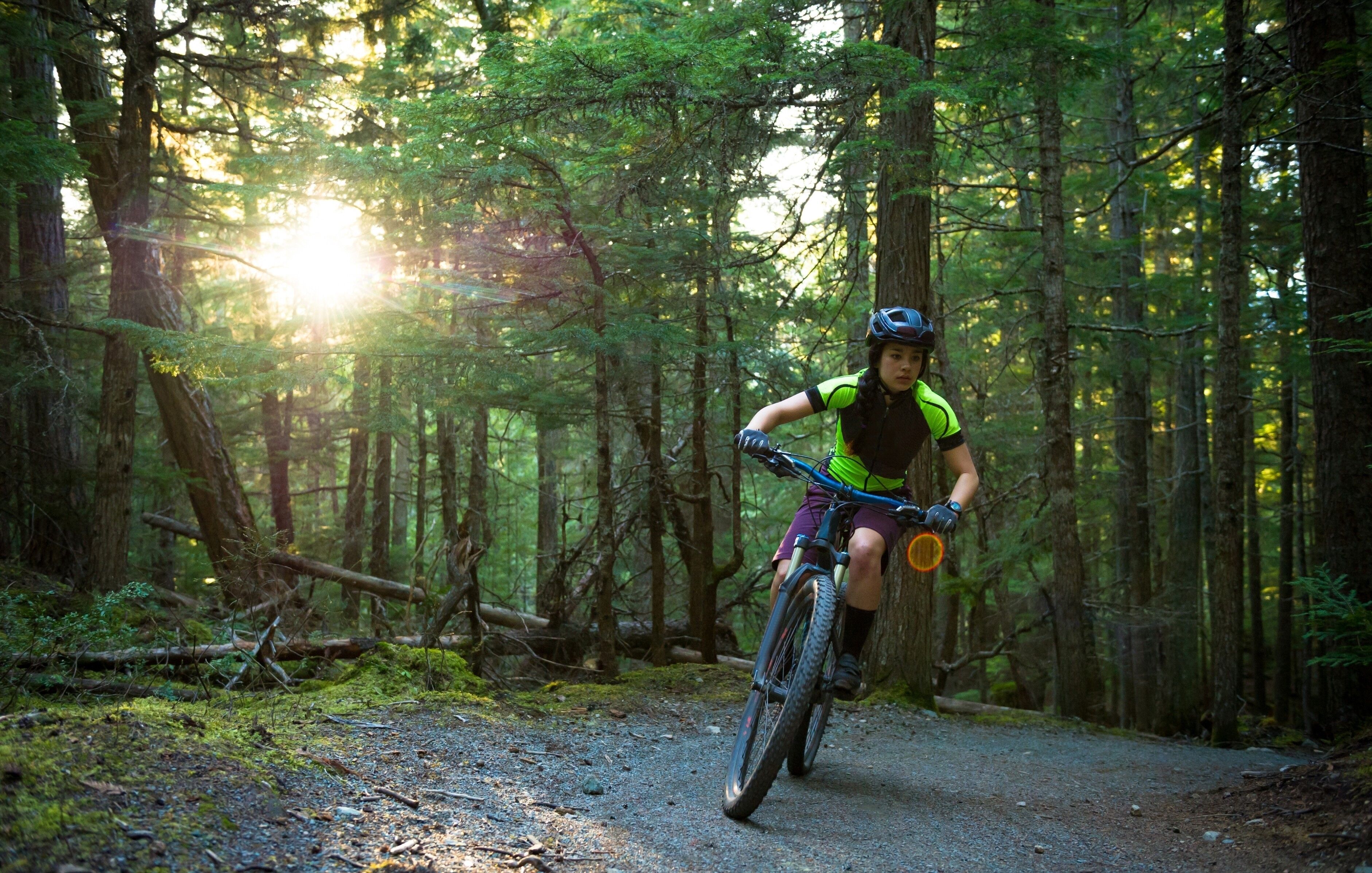 Una persona andando en bicicleta de montaña por un sendero forestal.
