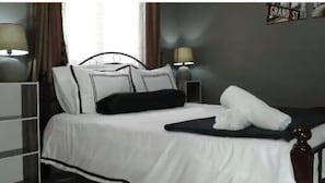 Une chambre d’hôtel avec un lit, deux tables de chevet, une lampe et un panneau mural.