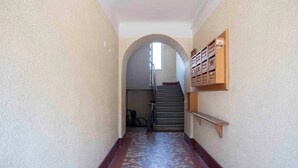 A hallway with a tiled floor, a wooden bench, and a staircase with a bicycle in the background.