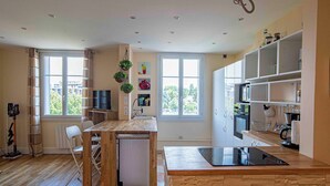 A modern kitchen with a wooden island, built-in appliances, and large windows.