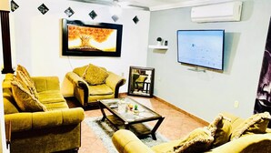 A living room with two yellow sofas, a coffee table, and a TV mounted on the wall.