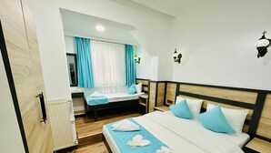 Habitación de hotel con una cama grande, una cama más pequeña, un escritorio y una ventana con cortinas.