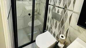 Un baño con ducha envuelta en vidrio, inodoro y lavamanos.