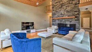 A spacious living room with a stone fireplace, white sofas, and a blue chair. - Magnificent Villa, Private Pool, Fire Pit w/Huge Backyard (Chester)