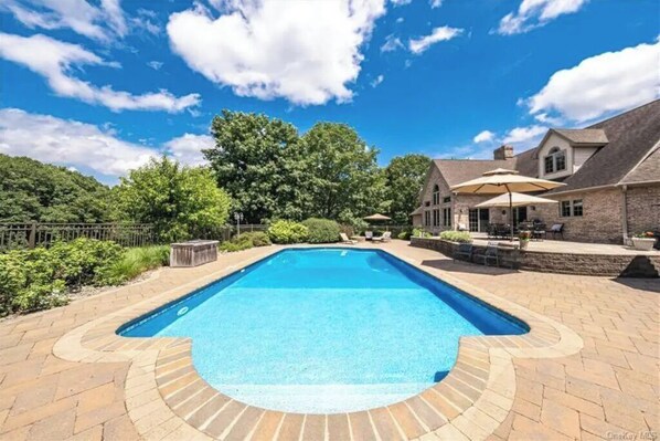 A rectangular swimming pool with a stone border, surrounded by a patio area with outdoor furniture and a covered seating area. - Magnificent Villa, Private Pool, Fire Pit w/Huge Backyard (Chester)