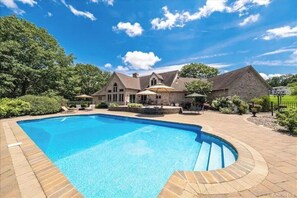 A large swimming pool with a stone deck, surrounded by a stone house with a wrap-around porch and umbrellas. - Magnificent Villa, Private Pool, Fire Pit w/Huge Backyard (Chester)
