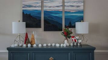 A dark blue dresser with two lamps, a vase with red berries, and a reindeer decoration.