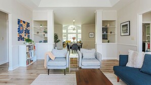 Un salón amplio con suelo de madera, dos sofás grises, una mesa de centro y una estantería.