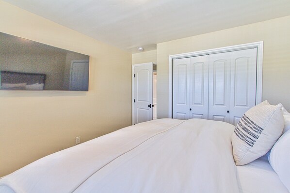 Een slaapkamer met een bed, witte muren en een deur.