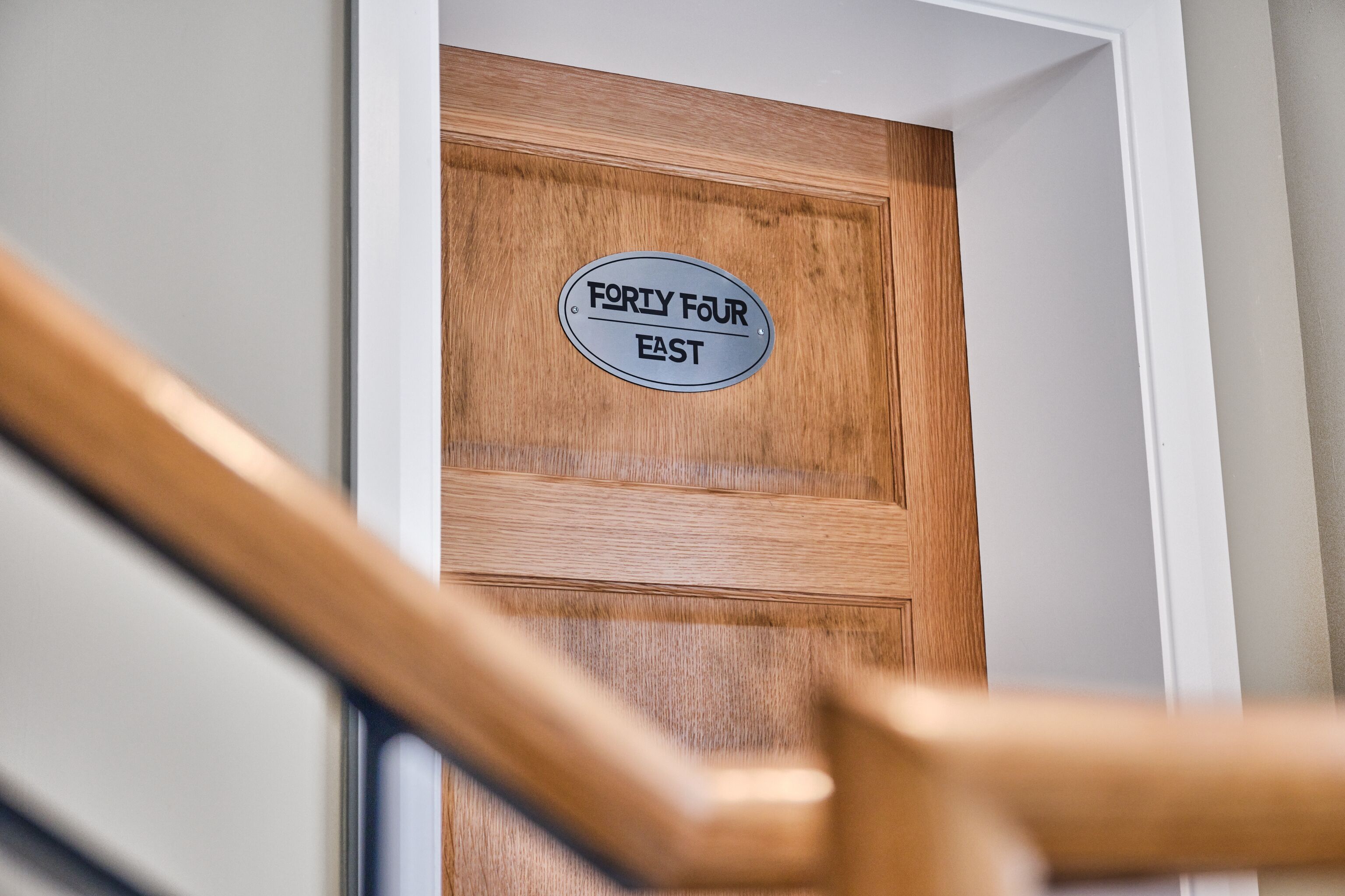 A wooden door with a sign that reads "FORTY FOUR EAST".