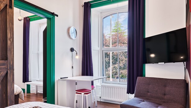 A room with a bed, a desk, a chair, and a window with curtains. - Forty Four North (Londonderry)