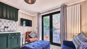 A modern living room with a blue sofa, a television mounted on the wall, and a sliding glass door leading to an outdoor area. - Forty Four North (Londonderry)