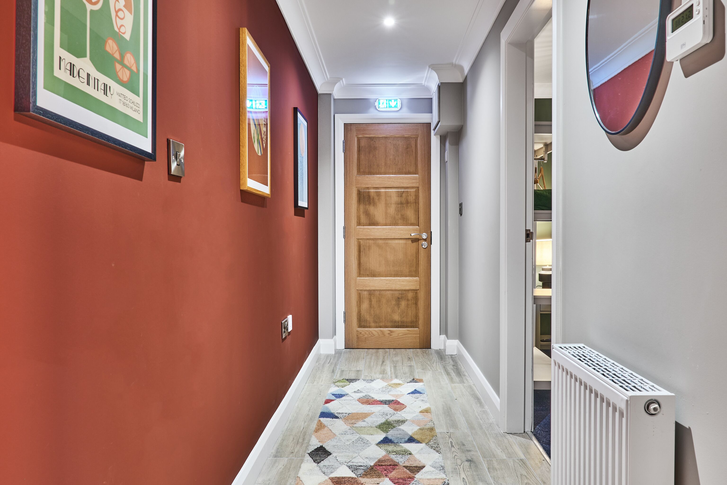 A hallway with a wooden door, a patterned rug, and a radiator.