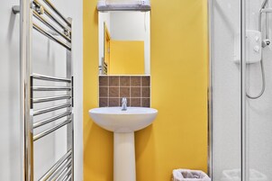Un baño con lavamanos blanco, espejo y cabina de ducha.