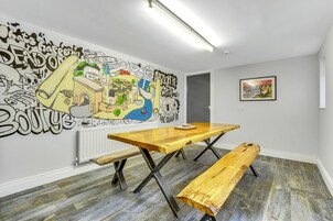 Una habitación con un mural grande, una mesa de madera, un banco y un cuadro enmarcado en la pared.
