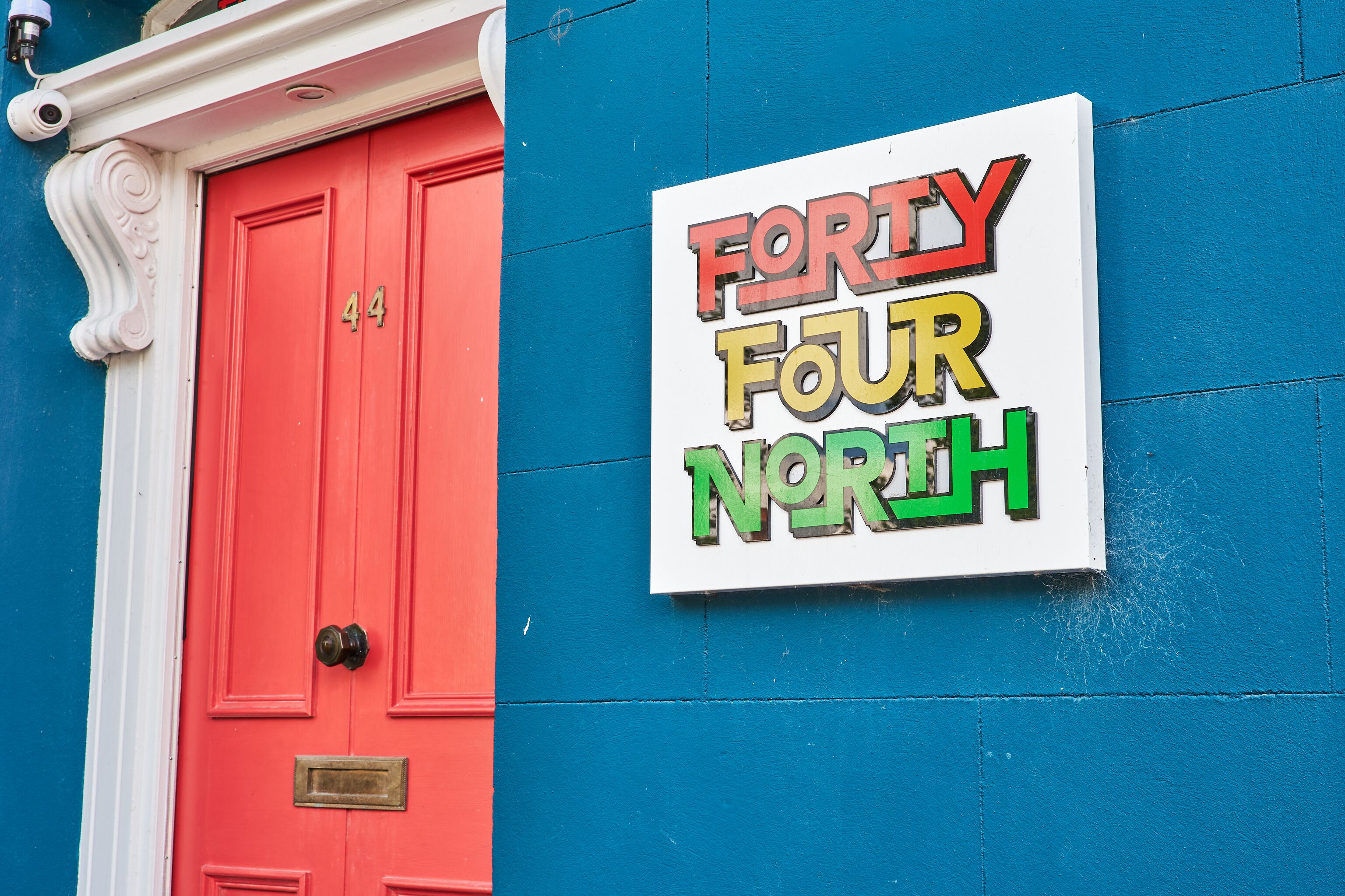 Un bâtiment avec une porte rouge et une enseigne sur laquelle on peut lire « Forty Four North ».