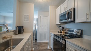 A modern kitchen with stainless steel appliances, a coffee maker, and a microwave. - Seas the Day Cottage (Gulfport)