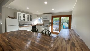 A modern kitchen with white cabinets, a wooden dining table, and a sliding glass door leading to a deck. - Welcome home in a welcoming town! (Littleton)
