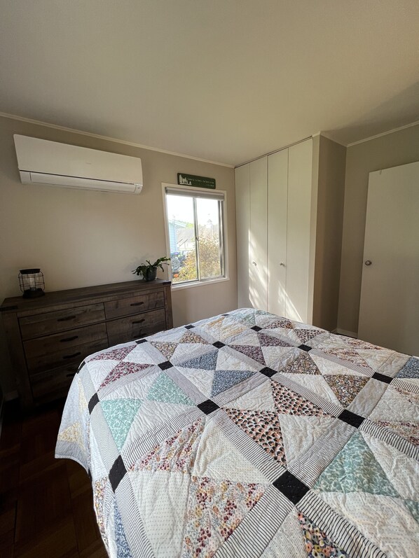 A bedroom with a large bed, a dresser, a window, and a door. - Welcome home in a welcoming town! (Littleton)