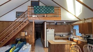 Een knus huisje met een slaapkamer op een entresol, een houten trap, keuken en eethoek.