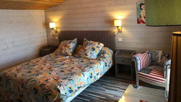 Una habitación acogedora con una cama, una silla y una lámpara.