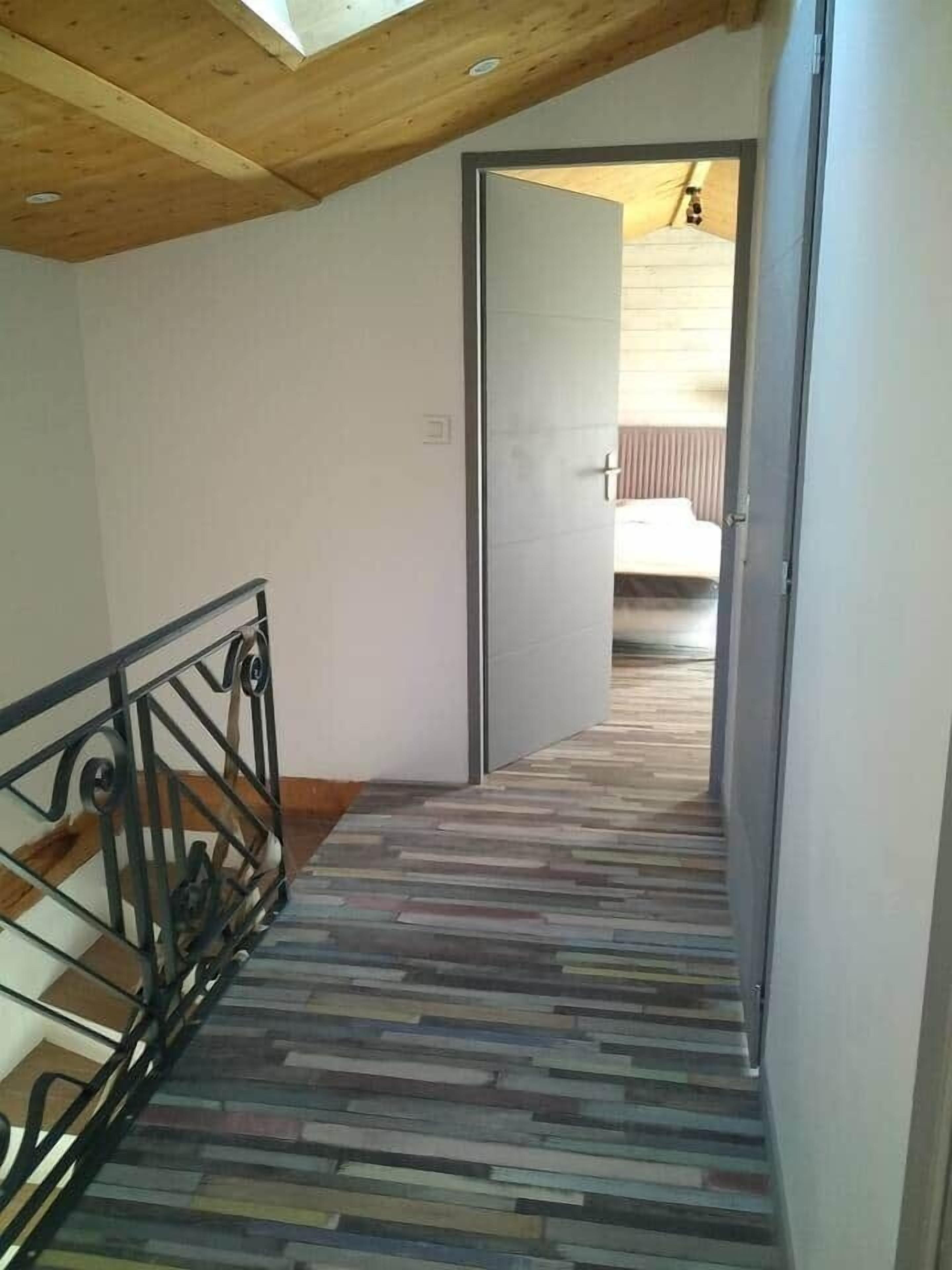 Corredor com teto de madeira e piso estampado, conduzindo a um quarto.
