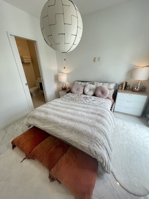 Een slaapkamer met een bed, nachtkastjes, een lamp en een hangende lamp.