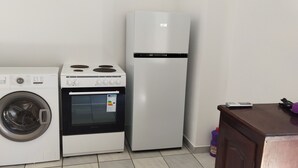 A compact kitchenette with a washing machine, a stove, and a refrigerator. - Perissa Art Villa - Kitchen & Washing Machine (Santorini)