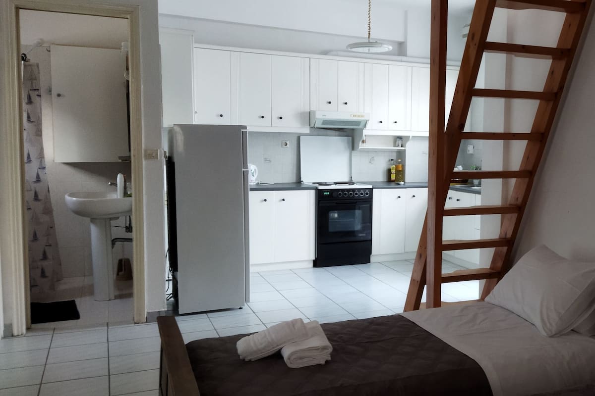 A bedroom with a bed, a nightstand, and a wooden ladder leaning against the wall.