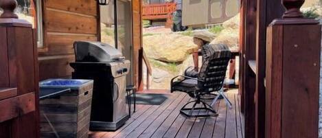A wooden deck with a grill and outdoor seating.