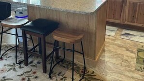 Cucina con mobili in legno, piano di lavoro in granito e angolo bar con sgabelli.
