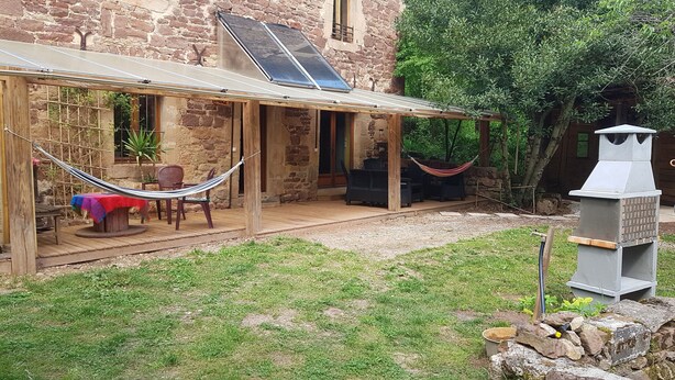 A rustic stone building with a covered patio, a hammock, outdoor furniture, and a barbecue grill. - Isolated house set in vineyards and woods (VALADY)