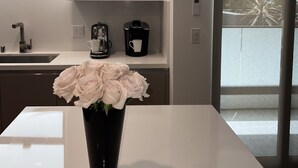 A modern kitchen with white cabinets, a coffee maker, and a vase with flowers on the counter.