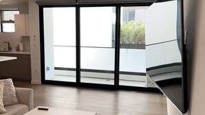 A modern living room with a white sofa, a coffee table, and a flat-screen TV mounted on the wall.