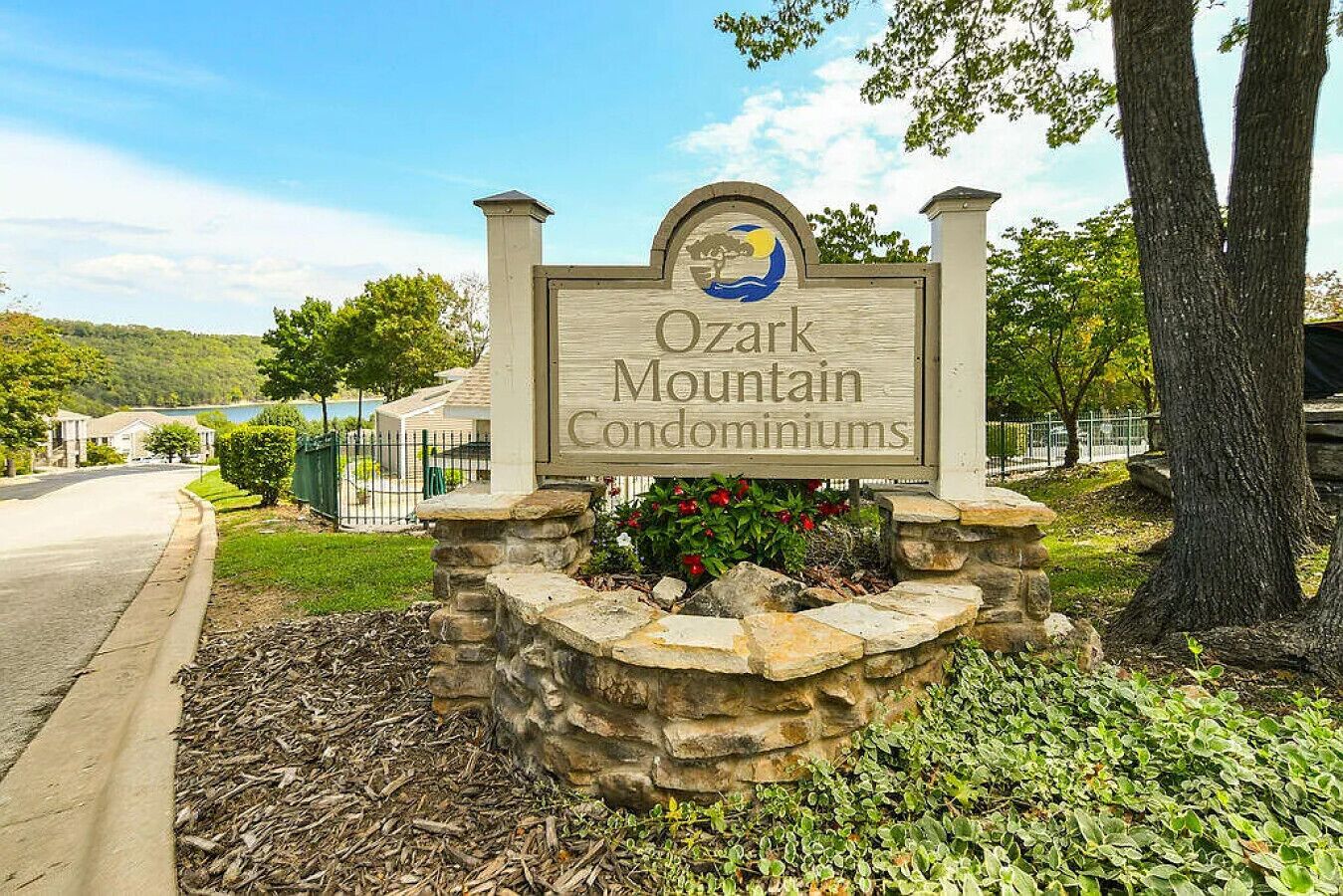 A sign for Ozark Mountain Condominiums with a stone base and a logo.