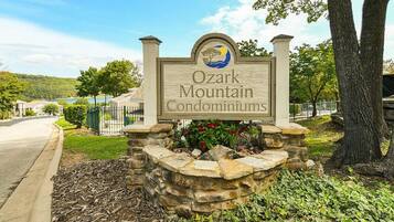 A sign for Ozark Mountain Condominiums with a stone base and a logo.