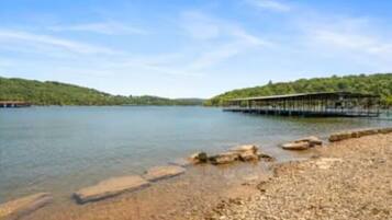 A calm lake with a wooden pier extending into the water, surrounded by hills.