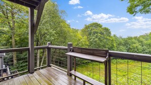 A wooden deck with a bench and railing overlooking a forested area. - Peaceful MTN Haven with Fireplace & Views (Banner Elk)