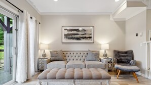 A modern living room with a tufted sofa, a grey armchair, and a large framed abstract painting on the wall. - Peaceful MTN Haven with Fireplace & Views (Banner Elk)