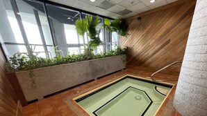 Zona de piscina con suelo de baldosas, un cartel de 'no acceso' y una jardinera con plantas.