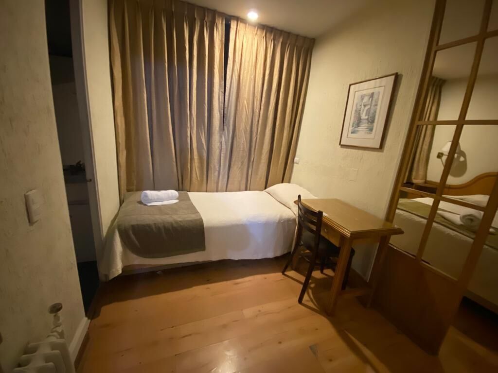 Ein kleines, gemütliches Zimmer mit einem Bett, einem Schreibtisch und einem Stuhl.