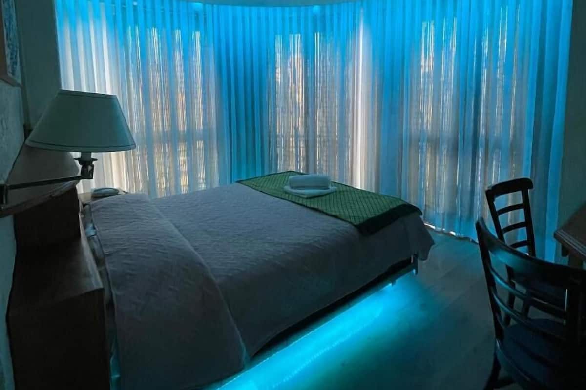 A hotel room with a bed, a desk, and a chair.