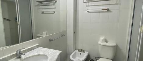 Un baño con lavamanos blanco, un bidé y un inodoro.